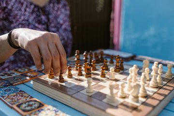A player hand is placed on a pawn as he considers a move.