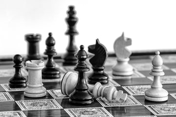 Black and white image of chess pieces on a board with defeated king
