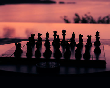 Chess board with pieces against a sunset background-h