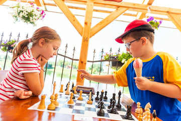 Young children playing chess and eating and ice cream