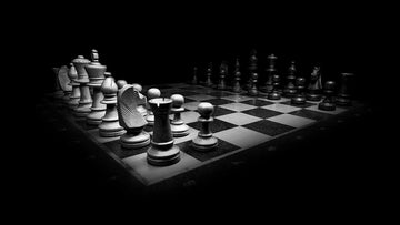 Black and white image of a chess table in the dark.